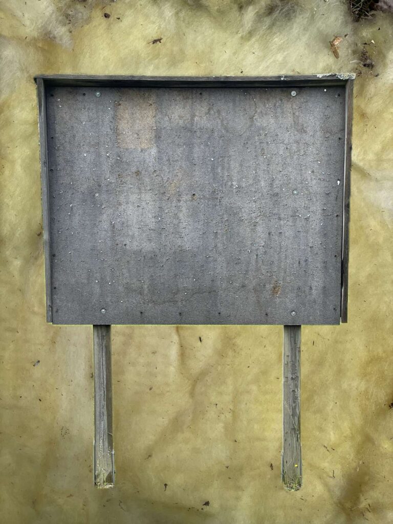 Inklippt foto av anslagstavla med gul glasfiberisolering som bakgrund
