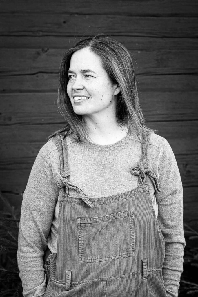 Svartvit porträttbild av Martha Kristensen ståendes framför mörk vägg, tittar åt sidan